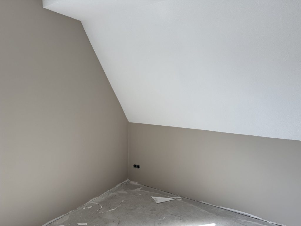 Zolderkamer met een schuine wand en kale muren, klaar om te laten afwerken